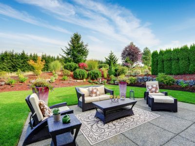 Impressive backyard landscape design. Cozy patio area with settees and table